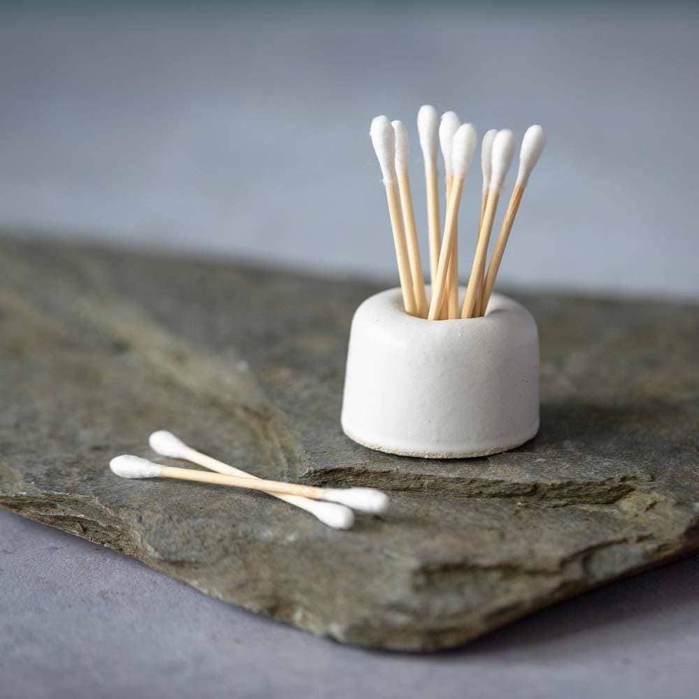Bamboo and cotton buds are shown in a white holder on top of the black slate.