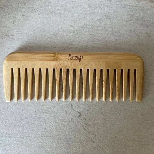 Wooden comb with &'keep' branding on a gray background