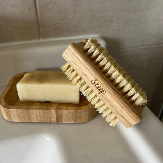 Wooden brush with natural bristles on a bathroom counter next to a bar of soap.