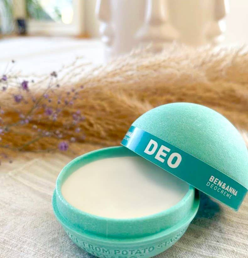 Green deodorant container with 'DEO' label on a textured surface with blurred background