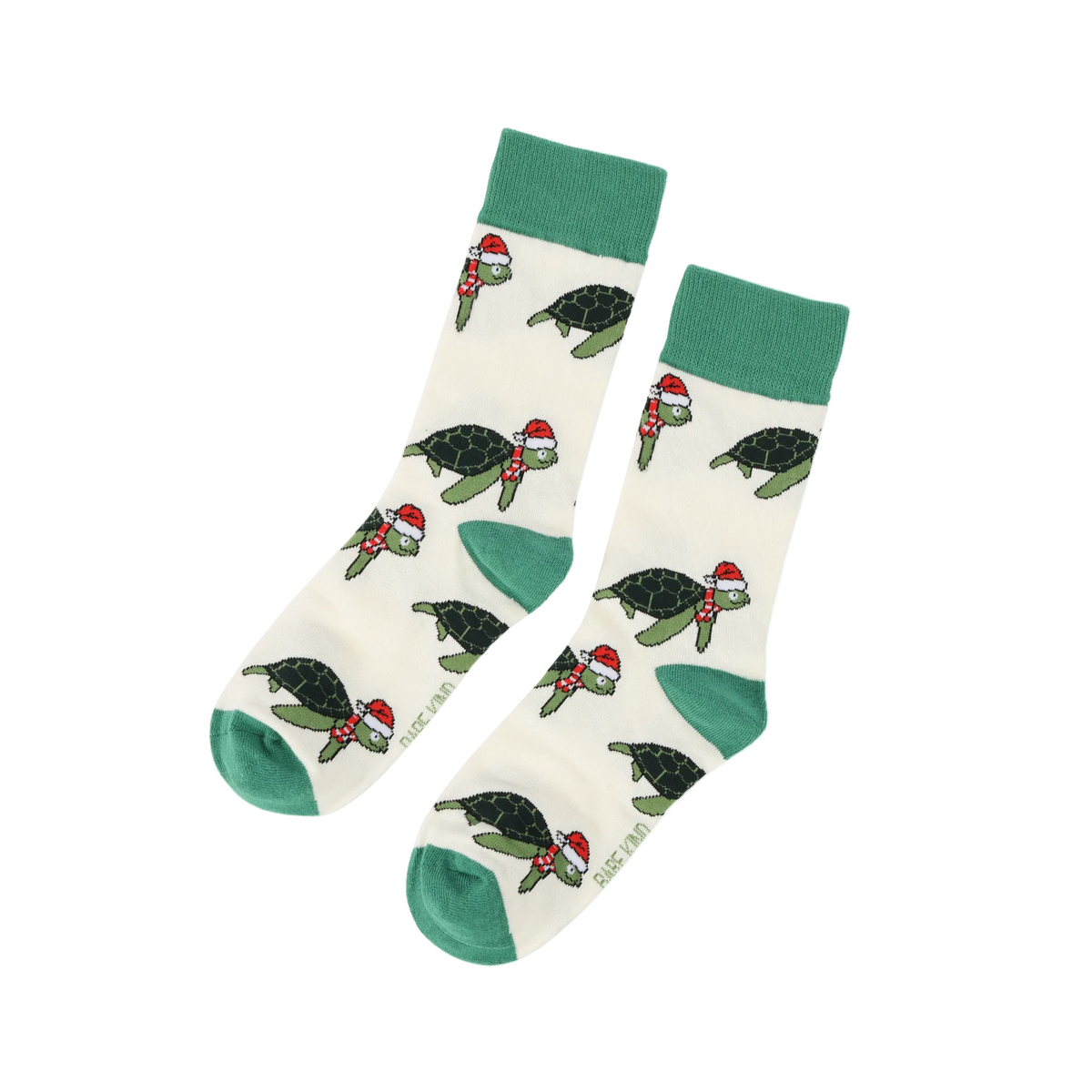 A pair of crew socks with a cream base featuring a repeating pattern of sea turtles wearing red Santa hats and scarves, with green cuffs, heels, and toes.