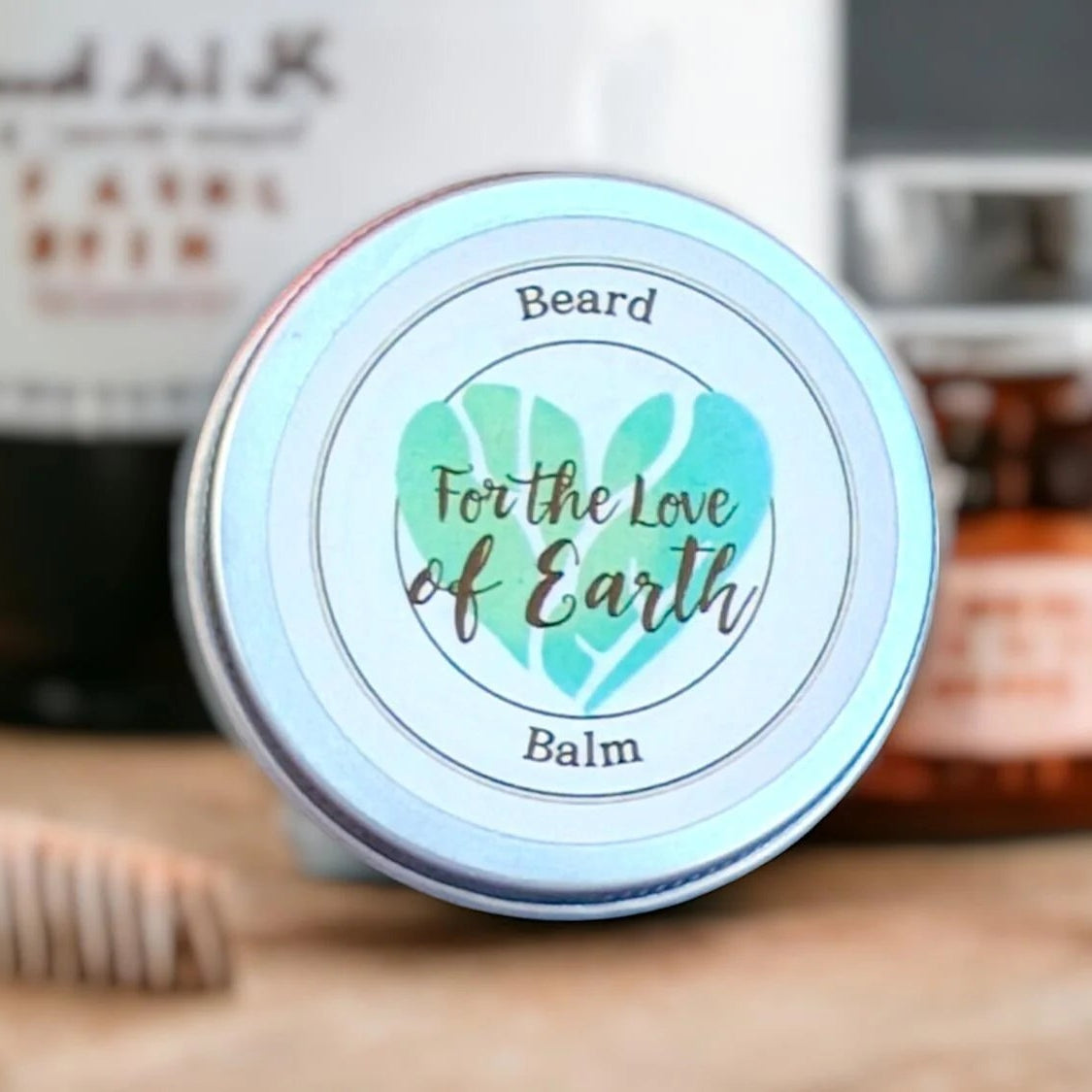 Beard balm container with 'For the Love of Earth' branding on a wooden surface with grooming tools.