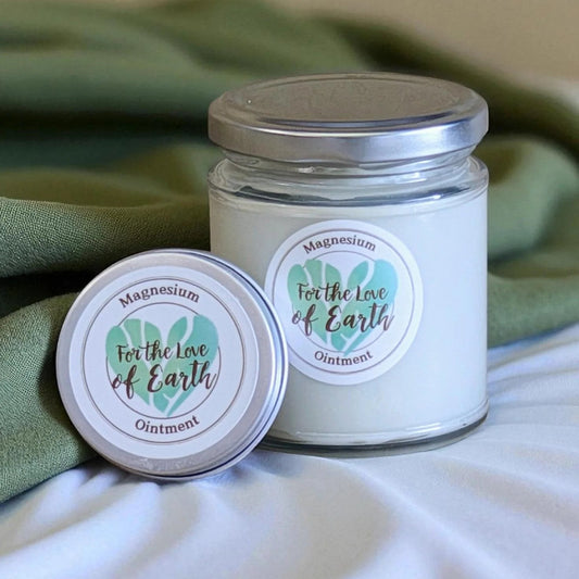 Jar and lid of 'For the Love of Earth' magnesium ointment on a green fabric background