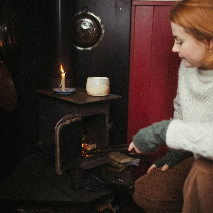 Person sitting next to stove making a hot chocolate in a candle lit room  