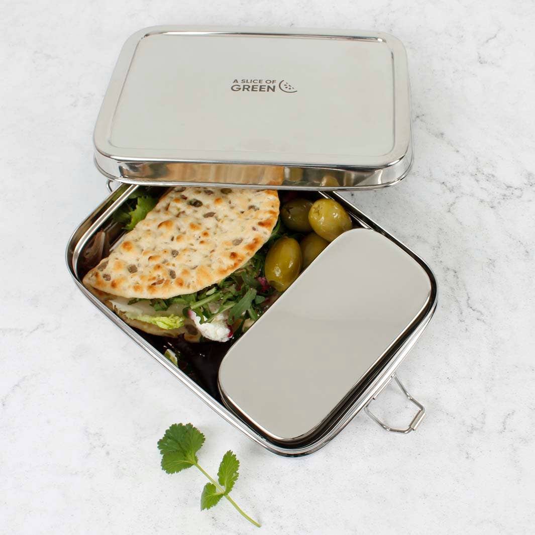 Metal lunch box and lid with a metal inserted container holding a sandwich and salad on a light background