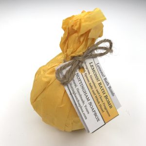 A wrapped bath bomb package tied with twine and attached a paper label reading 'Lemons! Bath Bombs' and 'NOTTINGHAM SOAPBOX', photographed on a plain white background.