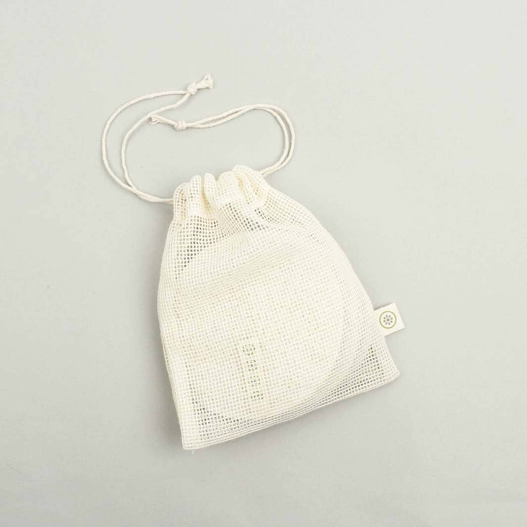An off-white mesh drawstring bag with a small fabric tag, containing a round white item, photographed on a light gray background.