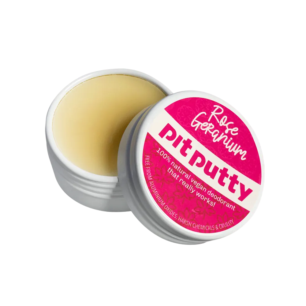 An open round white tin of Rose Geranium Pit Putty deodorant, showing the pale yellow balm inside, with the lid leaning against it. The lid has a bright pink label with white text.