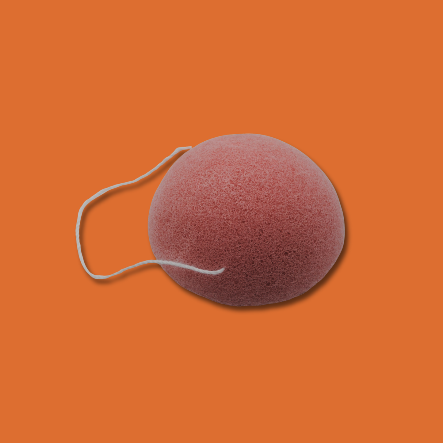 Pink konjac sponge with a string on an orange background