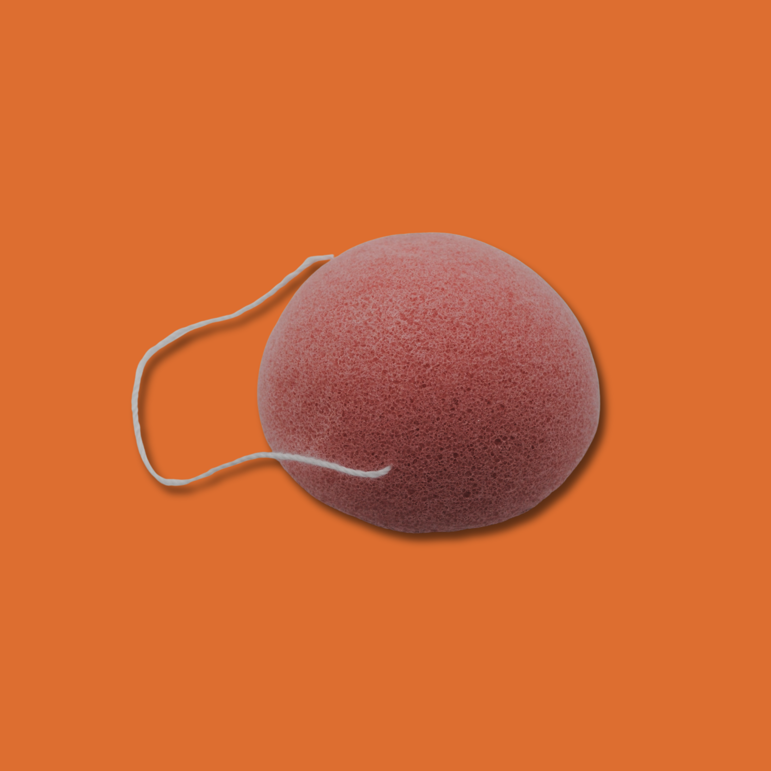 Pink konjac sponge with a string on an orange background